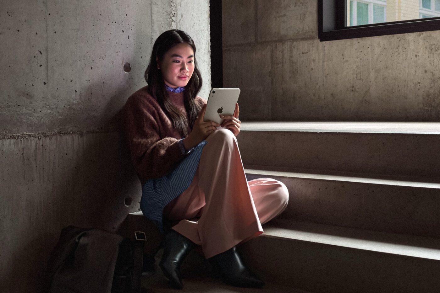 Een vrouw zit op een trap en leest op een iPad mini
