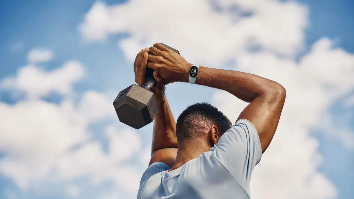 Man doet een triceps-oefening met een Fitbit Edge om zijn pols